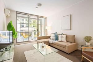 a living room with a couch and a glass table at A Comfortable Studio Near Darling Harbour in Sydney