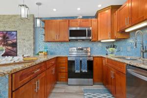 a kitchen with wooden cabinets and stainless steel appliances at Remodeled 1BR at Kihei Ali'i Kai with Free Parking! in Kihei