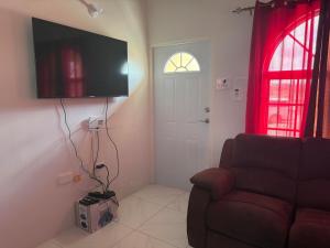 a living room with a couch and a flat screen tv at Finest Accommodation Phoenix Prk Village 2 lot 536 Phase 3 in Beckford Kraal