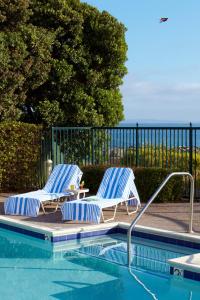 two blue and white chairs sitting next to a swimming pool at Beach House Half Moon Bay in Half Moon Bay