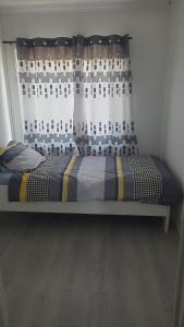 a bed in a room with a window with a curtain at Une Maison chaleureuse in Lebbeke