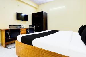 a bedroom with a bed and a desk and a television at Hotel O Mother Touch in Indirapuram