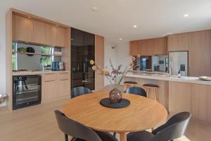 a kitchen with a wooden table with chairs and a vase with flowers at Havenview City Apartment in Nelson +24 photos
