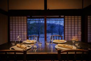 ein Tisch mit Stühlen und Weingläsern und ein Fenster in der Unterkunft 風の沢 in Kurihara