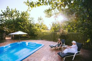 two people sitting in chairs next to a swimming pool at Holberry House in Nannup