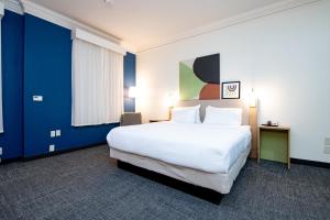 a hotel room with a large white bed and blue walls at Spark By Hilton Lafayette South in Lafayette