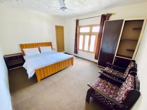 a bedroom with a bed and a chair in it at Vantage Lodge in Skardu