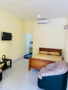 a bedroom with a bed and a couch and a tv at Great Victoria Palace in Ratnapura