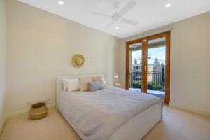 a white bedroom with a large bed and a window at Aria House - Henley Beach - Family Holiday Beachside BBQ in Henley Beach