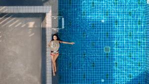 a woman is swimming in a swimming pool at Citrus Patong Hotel by Compass Hospitality in Patong Beach