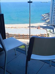 una mesa y una silla en un balcón con vistas a la playa en E1 Studios, Sea & Beach Views, High Floor, en Gibraltar