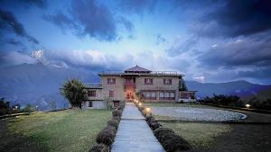 una casa grande en un campo con una montaña en Resort Thasang Village, en Lete