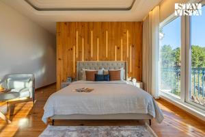 Un dormitorio con una cama y una ventana grande. en StayVista at Chestnut Manor with Lawn, BBQ, Bonfire, en Kasauli