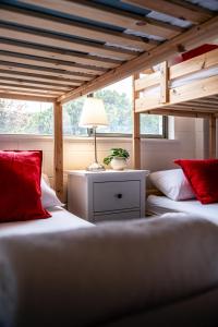 two beds with red pillows and a lamp in a room at Nine Mile House in Swansea