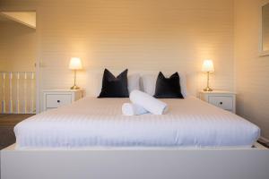 a large white bed with black pillows and two lamps at Nine Mile House in Swansea