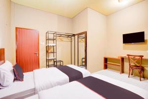 a room with two beds and a desk and a television at Collection O Padang City Center Near Transmart Padang Formerly De Orchids in Padang +35 photos
