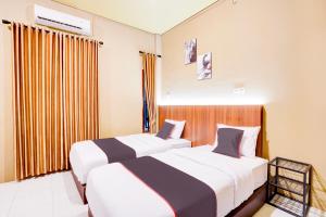 a hotel room with two beds and a window at Collection O Padang City Center Near Transmart Padang Formerly De Orchids in Padang
