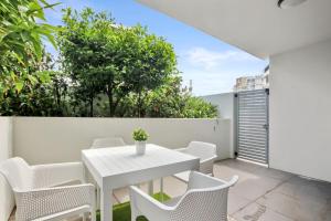 a white dining table and chairs on a balcony with trees at Aquaview Unit 103, 29 Canberra Tce, Kings Beach in Caloundra