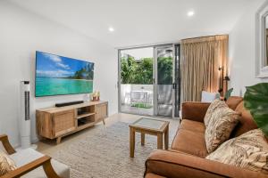 a living room with a couch and a flat screen tv at Aquaview Unit 103, 29 Canberra Tce, Kings Beach in Caloundra