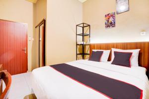 a bedroom with a large white bed with blue pillows at Collection O Padang City Center Near Transmart Padang Formerly De Orchids in Padang