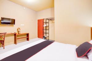 a bedroom with a bed and a desk at Collection O Padang City Center Near Transmart Padang Formerly De Orchids in Padang