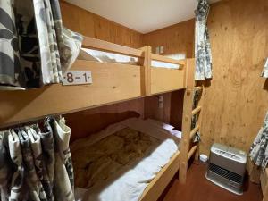 a bunk bed in a wooden room with a bed in it at Guesthouse Wanokaze mix domitory / Vacation STAY 32202 in Otaru