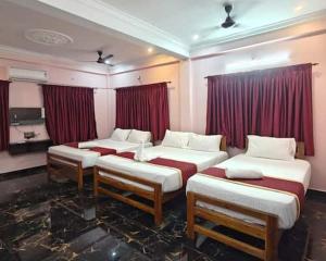 three beds in a room with red curtains at RD Resort in Pondicherry