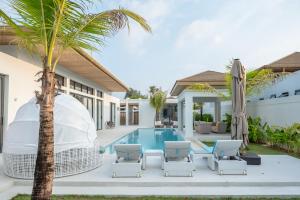 a villa with a pool and a palm tree at Mouana Breeze Mai Khao 5-bedroom Pool Villa 9910 in Mai Khao Beach
