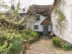 ein altes Cottage mit einem Strohdach und einem Garten in der Unterkunft 3 Cumberland Cottages in Kingsbridge