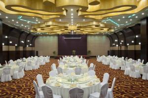 une grande salle de banquet avec des tables et des chaises blanches dans l'établissement Holiday Inn Xi'an Greenland Century City By IHG, à Xi'an 54 autres photos