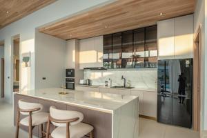 a kitchen with a large island with stools at Mouana Breeze Mai Khao 5-bedroom Pool Villa 9910 in Mai Khao Beach
