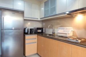 Una cocina con gabinetes blancos y un refrigerador de acero inoxidable. en Uptown BGC Spacious Unit - 1 Queen bed and Bunkbed, en Manila