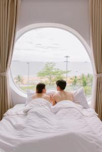 due uomini seduti a letto che guardano fuori dalla finestra di Đào Hoa Homestay a Quy Nhon