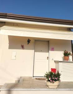 a white building with two potted plants and a door at La Casina di Nonna Altea in Massa