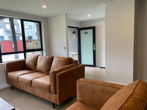 a living room with a brown couch and a window at Blues Air 3A - Thredbo in Thredbo