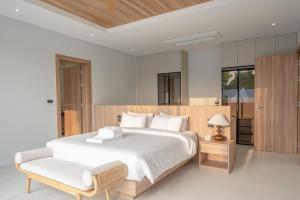 a bedroom with a large white bed and a chair at Mouana Breeze Mai Khao 5-bedroom Pool Villa 9910 in Mai Khao Beach +59 photos
