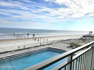 a balcony with a swimming pool and a beach at Direct Oceanfront Coastal Bliss in Daytona Beach