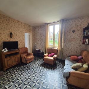 un soggiorno con divano, sedie e TV di La fermette d'etinehem a Étinehem