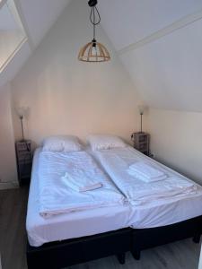 Hello Noordwijk - Zomerhuis Toekomststraat 8 في نوردفايك أن زي: سرير في غرفة نوم تحت وحدة إضاءة