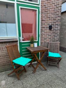 Hello Noordwijk - Zomerhuis Toekomststraat 8 في نوردفايك أن زي: طاولة خشبية وكرسيين بجانب مبنى