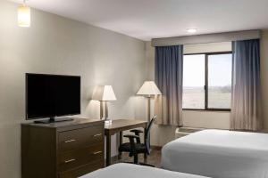 a hotel room with a desk with a television and a bed at Baymont by Wyndham Moses Lake in Moses Lake