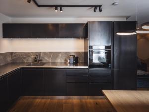 a kitchen with black cabinets and stainless steel appliances at Paradeis Apartments in Mühlbach