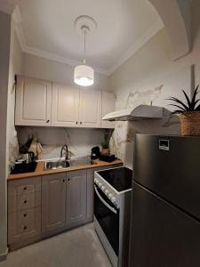 una cucina con mobili bianchi e un frigorifero nero di Finikas Apartment R203 a Corfu International Airport I Kapodistrias