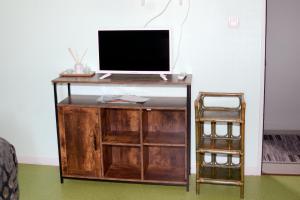 a television on a wooden stand with a chair at Le Perroquet Bleu in La Chapelle-Blanche-Saint-Martin