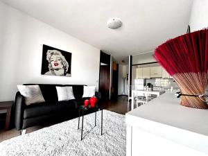 a living room with a black couch and a table at Blue wave apartment by the sea in Lignano Sabbiadoro