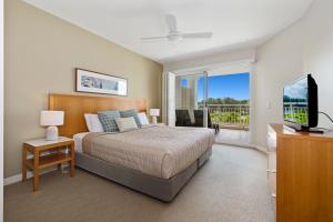 a bedroom with a bed and a television and a balcony at Garden View Apartment in Mantra Salt Beach Resort by uHoliday - 2BR, 1BR and Hotel Room configurations available in Kingscliff