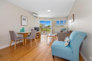 a living room with a blue chair and a table at Garden View Apartment in Mantra Salt Beach Resort by uHoliday - 2BR, 1BR and Hotel Room configurations available in Kingscliff +14 photos