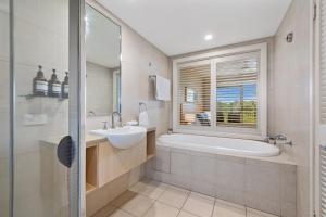 a bathroom with a sink and a tub and a window at Garden View Apartment in Mantra Salt Beach Resort by uHoliday - 2BR, 1BR and Hotel Room configurations available in Kingscliff