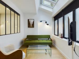 Una sala de estar con un sofá verde y una mesa de cristal. en Loft neuf derrière la Cathédrale, en Estrasburgo
