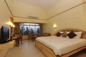 een slaapkamer met een bed en een televisie en een tafel bij Blue Country Resort in Panchgani